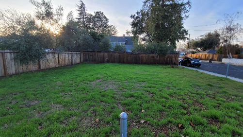 Vacant urban infill lot in the Bay Area with light vegetation and fencing